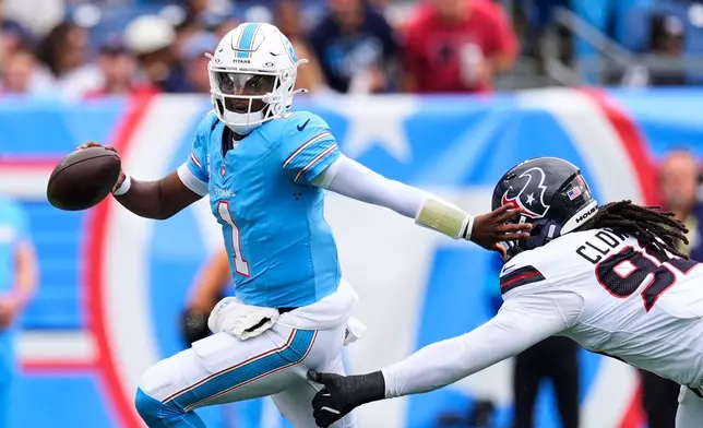Tennessee Titans quarterback Cam Ward (1) escapes pressure from Houston Texans defensive end Jadeveon Clowney, right, during the second half of an NFL football game in Nashville, Tenn., Sunday, Oct. 11, 2026. (AP Photo/George Walker IV)