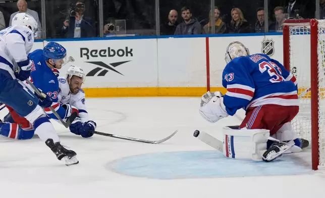 Tampa Bay Lightning's Zemgus Girgensons, second from right, tries to get a shot off after being held by New York Rangers' Adam Fox, left, during the first period of an NHL hockey game in New York, Tuesday, Oct. 13, 2026. (AP Photo/Seth Wenig)