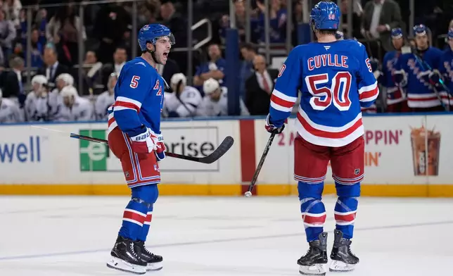 New York Rangers' Sean Durzi, left, celebrates a goal by Will Cuylle (50) during the second period of an NHL hockey game against the Tampa Bay Lightning in New York, Tuesday, Oct. 13, 2026. (AP Photo/Seth Wenig)