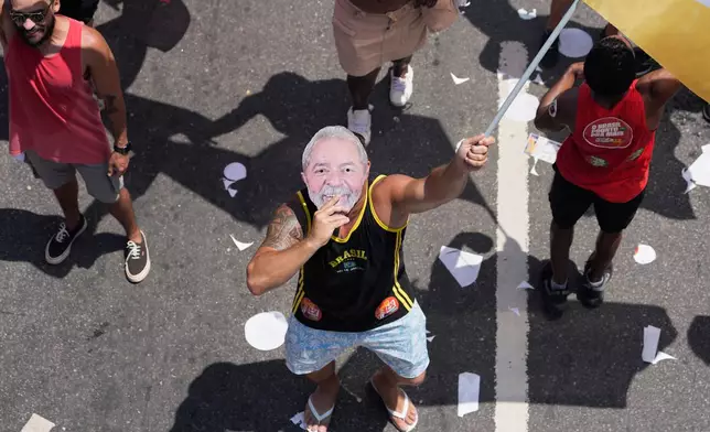 A supporter wears a mask of Brazilian President Luiz Inacio Lula da Silva, who is running for reelection, during his final campaign rally on Copacabana beach a day ahead of the presidential runoff election in Rio de Janeiro, Saturday, Oct. 24, 2026. (AP Photo/Silvia Izquierdo)