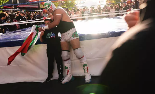 A Lucha Libre Volcánica wrestler takes a photo with a young fan during a Día de Muertos celebration at Pike Place Market, Friday, Oct. 23, 2026, in Seattle. (AP Photo/Lindsey Wasson)