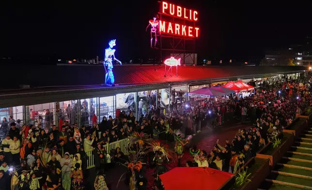 Dancers make their way down the street while performing in a parade during a Día de Muertos celebration at Pike Place Market, Friday, Oct. 23, 2026, in Seattle. (AP Photo/Lindsey Wasson)