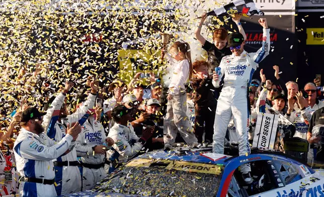 Kyle Larson, top right, celebrates with his children Owen, Audrey, and Cooper after his win in a NASCAR Cup Series auto race, Sunday, Oct. 25, 2026, in Talladega, Ala. (AP Photo/Butch Dill)