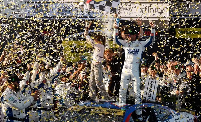 Kyle Larson, center right, celebrates with his children Owen, Audrey, and Cooper after his win in a NASCAR Cup Series auto race, Sunday, Oct. 25, 2026, in Talladega, Ala. (AP Photo/Butch Dill)