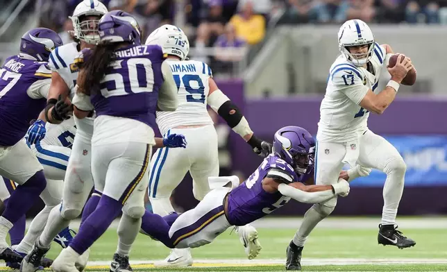 Indianapolis Colts quarterback Daniel Jones (17) tries to scramble away from Minnesota Vikings linebacker Eric Wilson, bottom, during the second half of an NFL football game in Minneapolis, Sunday, Oct. 25, 2026. (AP Photo/Ellen Schmidt)