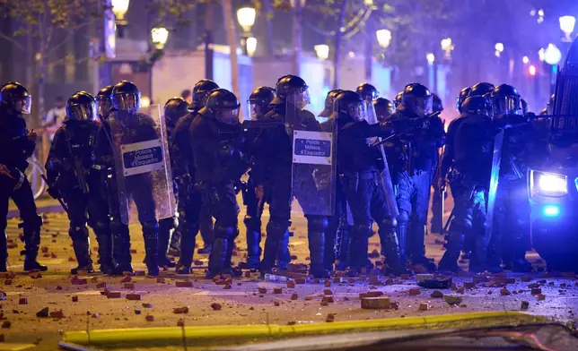 Riot police are pelted with rocks by protesters during clashes following a demonstration over Spain's housing crisis, hours after Prime Minister Pedro Sánchez announced an early general election, in Barcelona, Spain, Monday, Oct. 5, 2026. (AP Photo/Emilio Morenatti)
