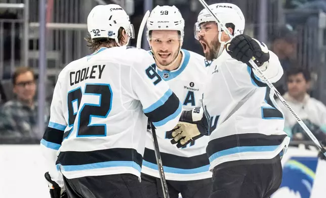 Utah Mammoth forward Logan Cooley, left, defenseman Mikhail Sergachev, middle, and defenseman MacKenzie Weegar celebrate a goal during the third periodof an NHL hockey game, Thursday, Oct. 22, 2026, in Seattle. (AP Photo/Stephen Brashear)