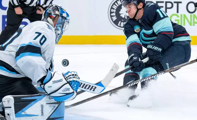 Seattle Kraken forward Mackie Samoskevich, right, fights Utah Mammoth goalie Karel Vejmelka for a loose puck in front of the net during the third period of an NHL hockey game, Thursday, Oct. 22, 2026, in Seattle. (AP Photo/Stephen Brashear)