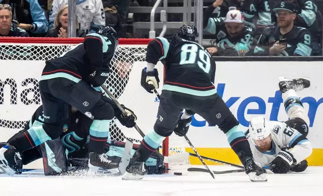 Utah Mammoth forward Lawson Crouse, right, loses control of the puck against Seattle Kraken defenseman Ryker Evans, left, and forward Frederick Gaudreau during the third period of an NHL hockey game, Thursday, Oct. 22, 2026, in Seattle. (AP Photo/Stephen Brashear)