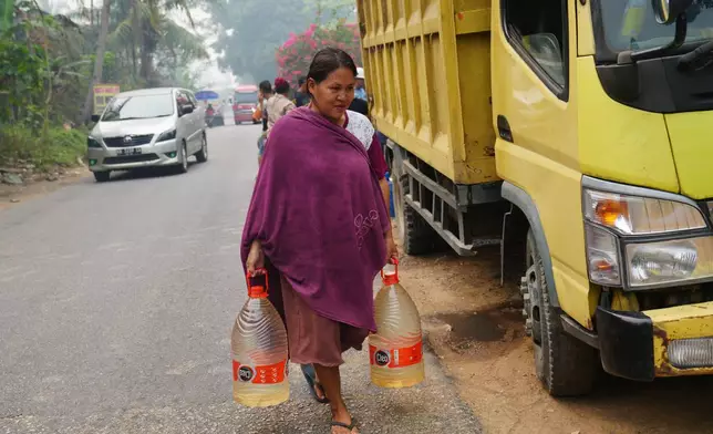 Sriwati, a shopkeeper and mother, carries two containers filled with clean water during a drought in Sanggau, West Kalimantan, Indonesia, Friday, Sept. 11, 2026. (AP Photo/Tatan Syuflana)