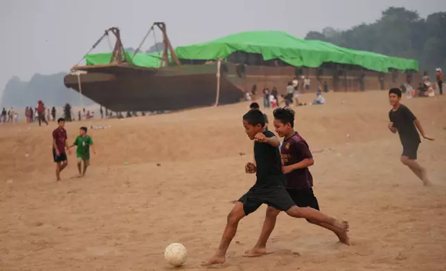 Kids play soccer near a barge stranded on a dry riverbed of the Kapuas River amid a drought in Sekadau, West Kalimantan, Indonesia, Friday, Sept. 11, 2026. (AP Photo/Tatan Syuflana)