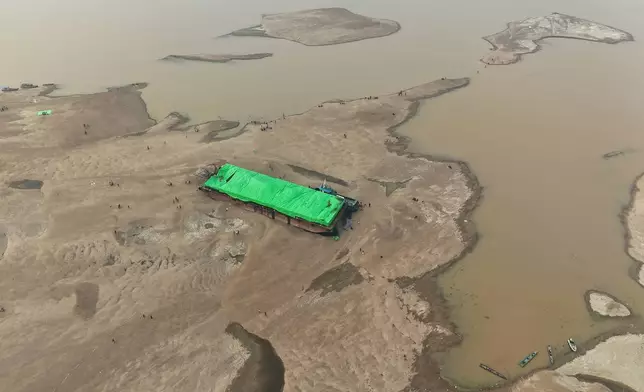 People surround a barge that is stranded on a dry riverbed of the Kapuas River amid a drought in Sekadau, West Kalimantan, Indonesia, Friday, Sept. 11, 2026. (AP Photo/Tatan Syuflana)