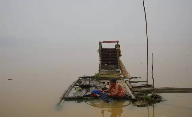 A woman washes clothes on a floating wooden platform along the Kapuas River amid haze in Sanggau, West Kalimantan, Indonesia, Friday, Sept. 11, 2026. (AP Photo/Tatan Syuflana)