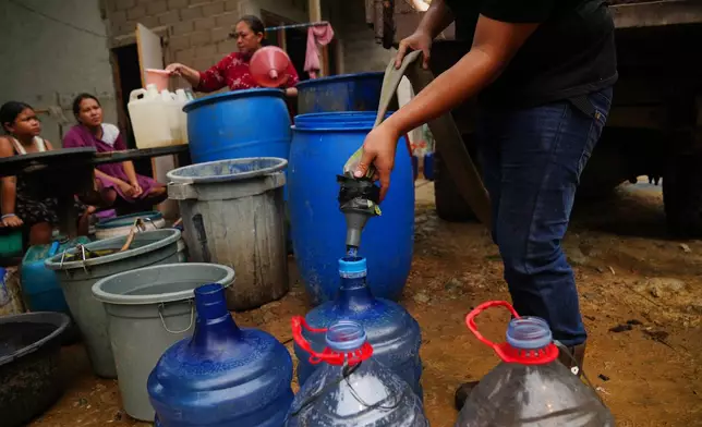 A resident fills their container with clean water as others wait for their turn from a tanker truck amid a drought in Sanggau, West Kalimantan, Indonesia, Friday, Sept. 11, 2026. (AP Photo/Tatan Syuflana)