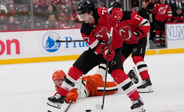 Anaheim Ducks' Drew Helleson, bottom, tries to block a shot attempt by New Jersey Devils' Luke Evangelista (77) during the second period of an NHL hockey game in Newark, N.J., Thursday, Oct. 22, 2026. (AP Photo/Seth Wenig)