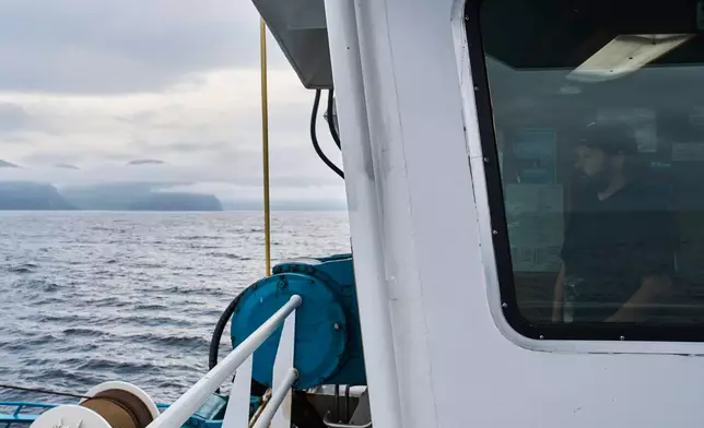 Maverick Blake, captain of the F/V Progress, looks out from the wheelhouse as he navigates his way out of Dutch Harbor, Alaska, Tuesday, July 21, 2026. (AP Photo/Annika Hammerschlag)