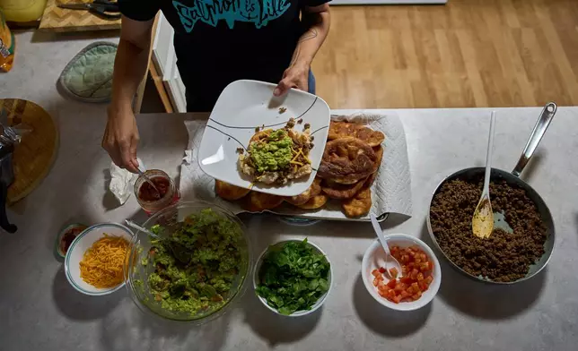 Brooke Woods serves herself moose meat tacos while wearing a shirt that reads "Salmon is Life" at her home in Rampart, Alaska, Sunday, July 12, 2026. (AP Photo/Annika Hammerschlag)