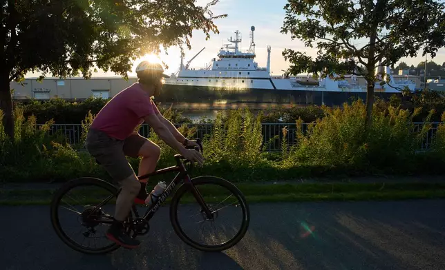 A cyclist bikes past the American Empress II, a trawler operated by Seattle-based American Seafoods in Seattle, Tuesday, Oct. 6, 2026. (AP Photo/Annika Hammerschlag)