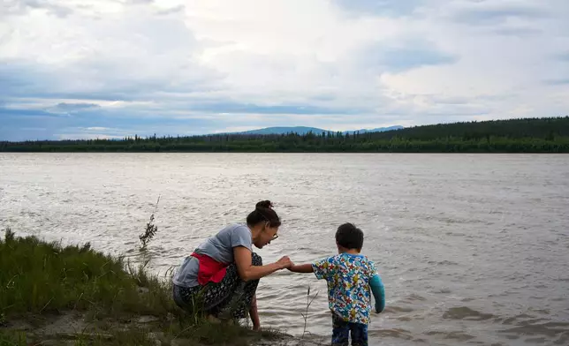 Brooke Woods and her son Lewis Thomas play in the Yukon River in Rampart, Alaska, Saturday, July 11, 2026. (AP Photo/Annika Hammerschlag)