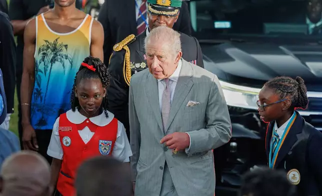 Britain's King Charles III is escorted by students as he leaves The Future Bahamas Youth Rally and Exhibition at Clifford Park in Nassau, Bahamas, Tuesday, Oct. 27, 2026. (AP Photo/Tim Aylen)