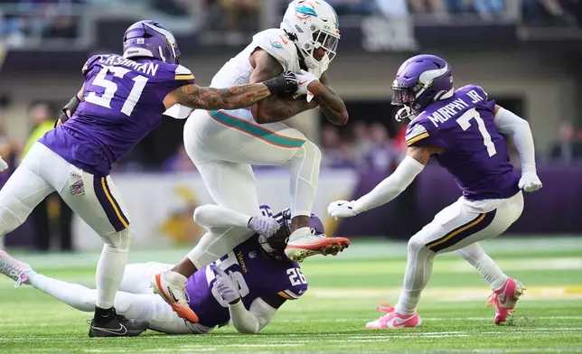 Miami Dolphins running back Ollie Gordon II, top, runs the ball as Minnesota Vikings linebacker Blake Cashman (51), safety Theo Jackson (26) and cornerback Byron Murphy Jr. (7) try to stop him during the first half of an NFL football game Sunday, Oct. 4, 2026, in Minneapolis. (AP Photo/Abbie Parr)