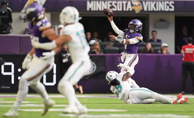 Minnesota Vikings quarterback Kyler Murray, top right, attempts a pass as Miami Dolphins defensive end Rodney McGraw (59) tries to stop him during the first half of an NFL football game Sunday, Oct. 4, 2026, in Minneapolis. (AP Photo/Abbie Parr)