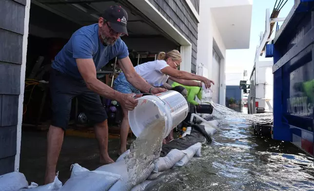 Members of the Deakins family remove floodwater from their garage in Huntington Beach, Calif., Wednesday, Oct. 28, 2026. (AP Photo/Jae C. Hong)