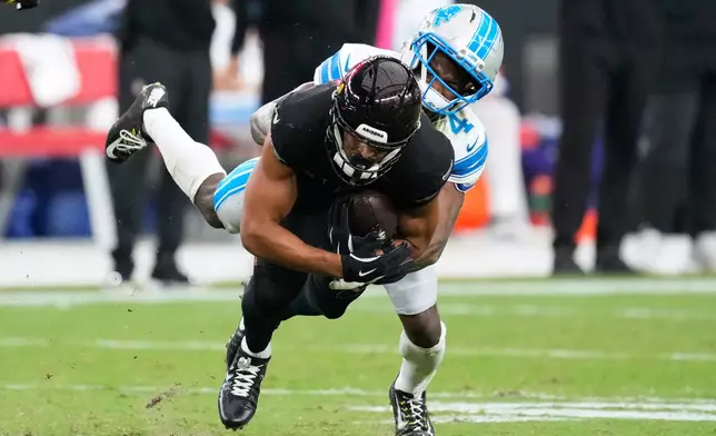 Detroit Lions cornerback D.J. Reed (4) tackles Arizona Cardinals wide receiver Michael Wilson (14) during the second half of an NFL football game in Glendale, Ariz., Sunday, Oct. 11, 2026. (AP Photo/Ross D. Franklin)