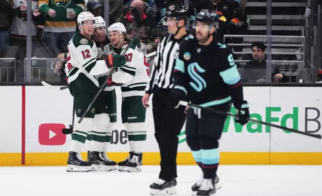 Minnesota Wild center Joel Eriksson Ek (14) celebrates scoring against the Seattle Kraken with left wing Matt Boldy (12) and left wing Kirill Kaprizov (97) during the second period of an NHL hockey game Saturday, Oct. 24, 2026, in Seattle. (AP Photo/Lindsey Wasson)