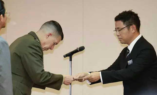 Okinawa Gov. Genta Koja, right, hands a letter of protest to U.S. Marine Corps Lt. Gen. Benjamin T. Watson at Okinawa prefectural office in Naha, Okinawa Monday, Oct. 5, 2026, after Japanese police arrested a U.S. Marine accused of robbing and killing a woman. (Kotaro Ueda/Kyodo News via AP)