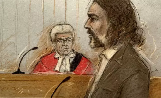 This court artist sketch by Elizabeth Cook shows Judge Mr Justice Bennathan looking on as Russell Brand appears at Southwark Crown Court, London, where he faces three charges of rape, indecent assault, and three counts of sexual assault, relating to six women, on Wednesday Oct. 28, 2026. (Elizabeth Cook/Press Association via AP)