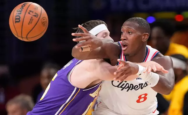 LA Clippers guard Kris Dunn, right passes while under pressure from Los Angeles Lakers guard Austin Reaves during the first half of an NBA basketball game Friday, Oct. 23, 2026, in Los Angeles. (AP Photo/Mark J. Terrill)