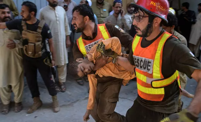 Rescue workers carry an injured boy after rescuing him from the rubble of a roof collapse at a private school, in Peshawar, Pakistan, Thursday, Oct. 15, 2026. (AP Photo/Muhammad Zubair)