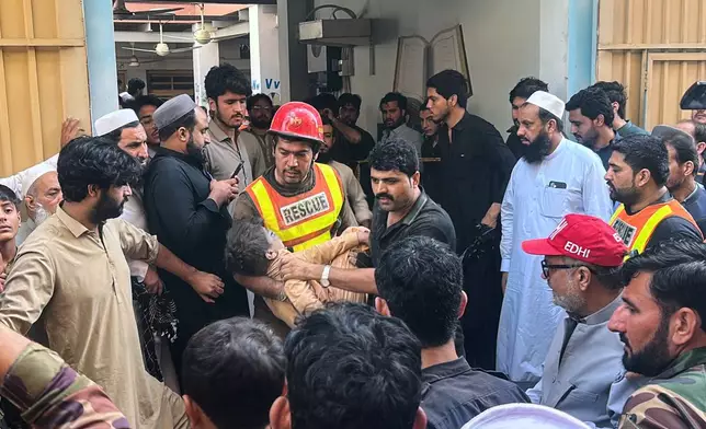 A rescue worker carries an injured child after rescuing him from the rubble of a roof collapse at a private school, in Peshawar, Pakistan, Thursday, Oct. 15, 2026. (AP Photo/Arif Khan)
