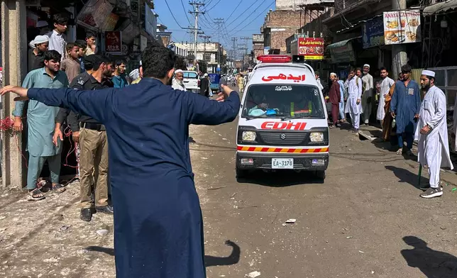 A volunteer clears the way for an ambulance transporting injured school children following a roof collapse at a private school in Peshawar, Pakistan, Thursday, Oct. 15, 2026. (AP Photo/Maaz Awan)