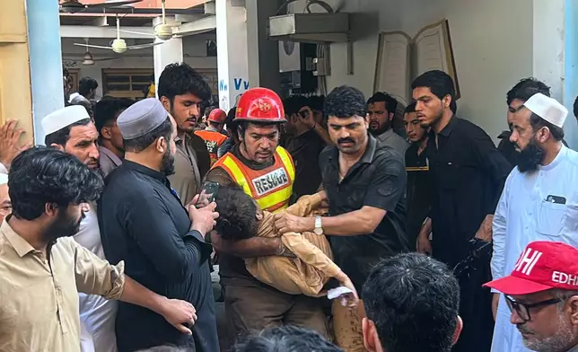 A rescue worker carries an injured child after rescuing him from the rubble of a roof collapse at a private school, in Peshawar, Pakistan, Thursday, Oct. 15, 2026. (AP Photo/Arif Khan)