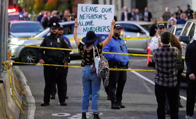A person holds a sign at the scene of a shooting as law enforcement work the area Thursday, Oct. 8, 2026, in New York. (AP Photo/Seth Wenig)