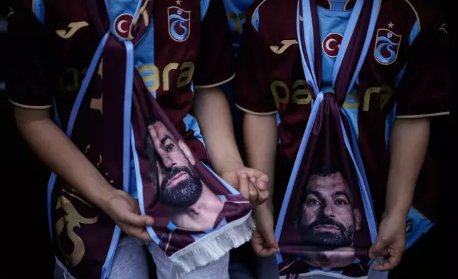 Two young Trabzonspor fans wearing the club's claret and light blue jerseys hold scarves featuring Egyptian soccer player Mohamed Salah in Trabzon, Turkey, Monday, Oct. 19, 2026. (AP Photo/Khalil Hamra)