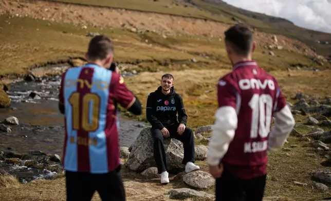 Trabzonspor fans pose for photographs on the same rock where the club's Egyptian soccer player Mohamed Salah posed for a photo he later shared on social media, in Trabzon province, along Turkey's Black Sea coast, Monday, Oct. 19, 2026. (AP Photo/Khalil Hamra)