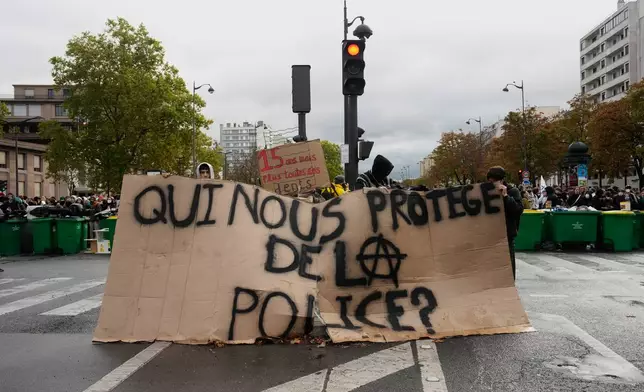 Students holds a board reading "Who protects us from the police?" as they stand in front of the Helene Boucher high school blockaded during a protest against under-resourced schools in Paris, Tuesday Oct. 13, 2026. (AP Photo/Teresa Suarez)
