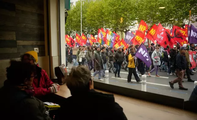 People sitting in a pub watch demonstrators during a protest on the sidelines of the far-right Rassemblement National (RN) congress in Orleans, France, Saturday, Oct. 24, 2026. (AP Photo/Teresa Suarez)