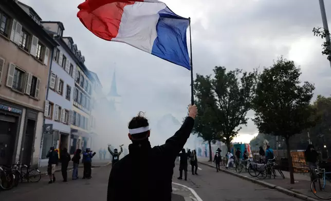 A protester holds a French flag during a demonstration against rising living costs in Strasbourg, France, Saturday, Oct. 24, 2026. (AP Photo/Jean-Francois Badias)