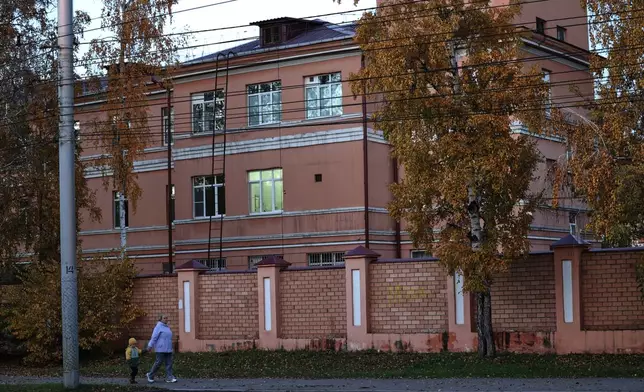 A woman with her child walks past the building of the Irkutsk Anti-Plague Research Institute of Siberia and the Far East in Irkutsk, Russia, on Wednesday, Oct. 7, 2026. (AP Photo)