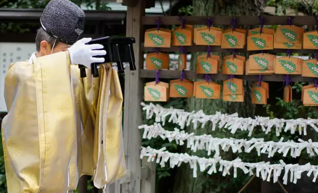 A Shinto priest carries a box containing doll-shaped paper talismans during a doll memorial ceremony at Dairokuten Sakaki Shrine in Tokyo, Tuesday, Oct. 13, 2026. (AP Photo/Eugene Hoshiko)