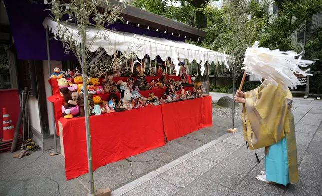 A Shinto priest performs a purification ritual in front of dolls and stuffed toys during a doll memorial ceremony at Dairokuten Sakaki Shrine in Tokyo, Tuesday, Oct. 13, 2026. (AP Photo/Eugene Hoshiko)