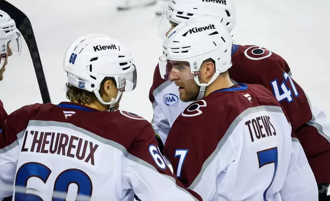 Colorado Avalanche's Devon Toews, front right, celebrates with teammates after his goal during the second period of an NHL hockey game against the Calgary Flames in Calgary, Alberta, Thursday, Oct. 8, 2026. (Jeff McIntosh/The Canadian Press via AP)