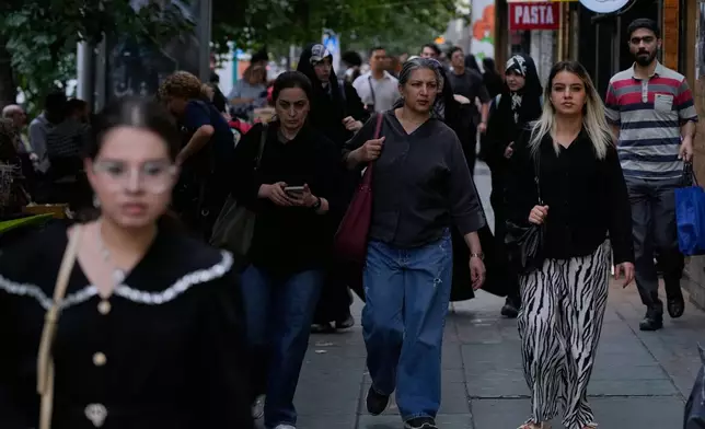 Pedestrians walk along Islamic Revolution street in Tehran, Tuesday, Oct. 6, 2026. (AP Photo/Vahid Salemi)