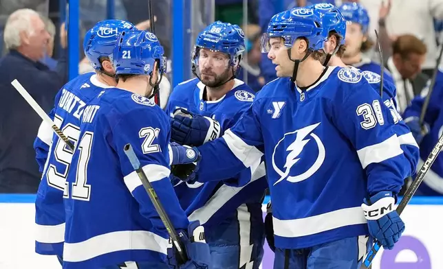 Tampa Bay Lightning right wing Nikita Kucherov (86, center) celebrates his goal against the Vancouver Canucks with teammates, including left wing Brandon Hagel (38) and center Brayden Point (21) during the second period of an NHL hockey game Saturday, Oct. 17, 2026, in Tampa, Fla. (AP Photo/Chris O'Meara)
