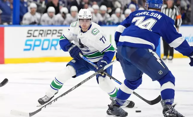 Vancouver Canucks center Filip Chytil (77) cuts towards Tampa Bay Lightning defenseman John Carlson (74) during the third period of an NHL hockey game Saturday, Oct. 17, 2026, in Tampa, Fla. (AP Photo/Chris O'Meara)
