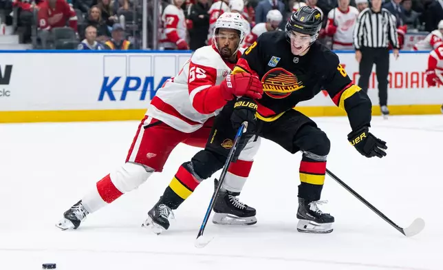 Detroit Red Wings' Keegan Kolesar (55) and Vancouver Canucks' Zeev Buium (8) vie for the puck during the second period of an NHL hockey game in Vancouver, British Columbia, Thursday, Oct. 22, 2026. (Ethan Cairns/The Canadian Press via AP)